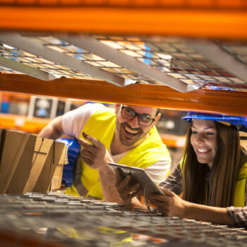 Warehouse workers counting boxes on shelves in large distribution warehouse.